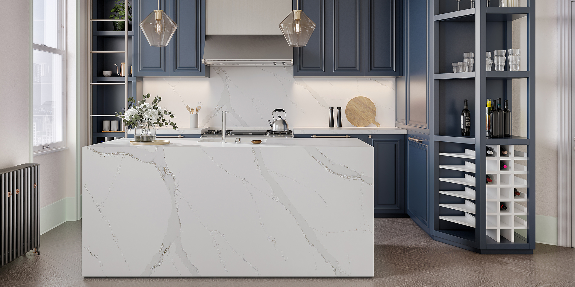 Two modern pendant lights hang above an eco-friendly quartz kitchen island. Blue cabinetry and soft under-cabinet lighting frame the same marble-look quartz backsplash in the backdrop.